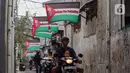 Pengendara sepeda motor melintas di bawah sejumlah bendera Palestina yang terpasang di Palmerah, Jakarta Barat, Sabtu (11/11/2023). (Liputan6.com/Angga Yuniar)