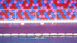Pria berenang di dekat 'The Mastaba', sebuah karya luar ruangan di danau Serpentine di Hyde Park, London (11/6). Mastaba adalah bangunan yang beratap datar, berbentuk balok dengan sisi-sisi yang miring. (AFP Photo/Niklas Hallen)