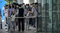 Karyawan yang mengenakan masker menunggu hasil tes COVID-19 mereka diperiksa untuk memasuki gedung perkantoran di kawasan pusat bisnis di Beijing, China, Selasa (31/5/2022). Penguncian COVID-19 di Shanghai telah mencekik ekonomi nasional dan sebagian besar mengurung jutaan orang di rumah mereka. (AP Photo/Mark Schiefelbein)