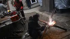 Relawan menyolder balok-I untuk membuat rintangan anti-tank yang dikenal sebagai landak Ceko di sebuah bengkel di Lviv, Ukraina barat (3/3/2022). Para relawan di Ukraina membuat rintangan tersebut untuk menghambat tank-tank Rusia masuk ke kota. (AFP/Daniel Leal)