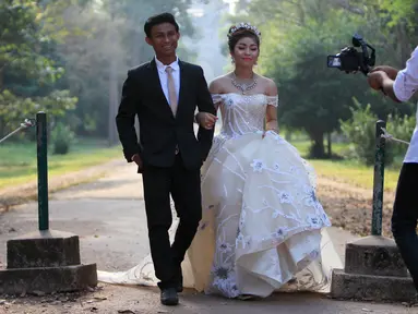 Sepasang pengantin baru melakukan foto pernikahan mereka di kompleks kuil Angkor Wat, sebuah candi ikonik dan bersejarah di Kamboja, 14 Maret 2018. Candi ini adalah jantung dan jiwa Kamboja serta menjadi kebangaan nasional. (AP Photo/Heng Sinith)