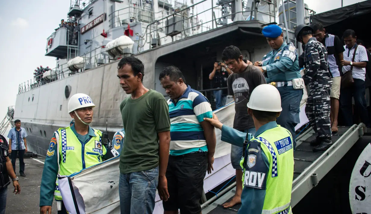 Anggota TNI AL mengawal sembilan tersangka dari sebuah kapal angkatan laut di Surabaya, Jawa Timur, Selasa (10/5). Sembilan tersangka akan dibawa ke Surabaya untuk menjalani pemeriksaan. (AFP PHOTO/JUNI KRISWANTO)