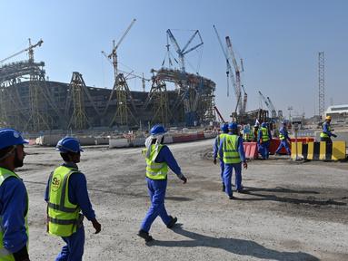 Pekerja melintas di depan pembangunan Stadion Lusail di Qatar, Jumat (20/12). Lusail akan menjadi stadion untyuk partai pembuka dan penutup piala dunia 2022 di Qatar. (AFP/Giuseppe Cacace)