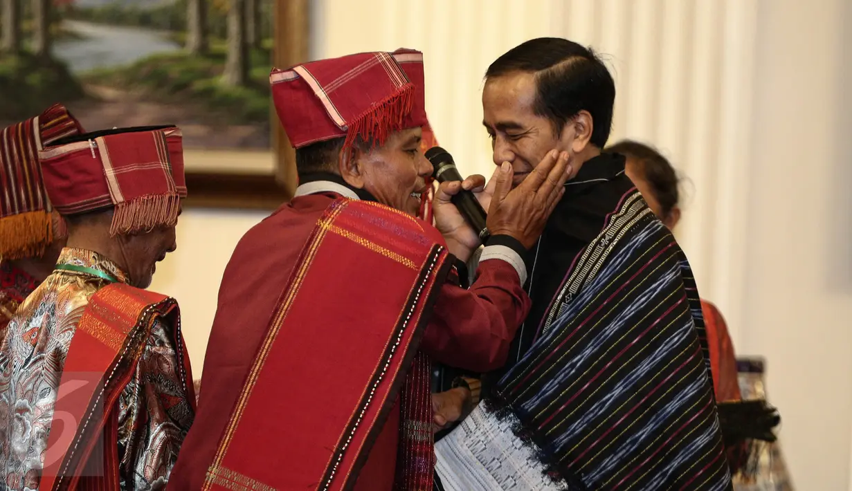 Pemangku Hutan Adat dari Tombak Haminjon (Kemenyan) Provinsi Sumatera Utara mengalungkan kain ulos kepada Presiden Joko Widodo (Jokowi) usai pencanangan pengakuan Hutan Adat di Istana Negara, Jakarta, Jumat (30/12). (Liputan6.com/Faizal Fanani)