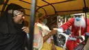 Penumpang bajaj menerima masker yang diberikan oleh presiden Angel Foundation dan pekerja sosial, Rufas Christian berkostum Sinterklas di persimpangan lalu lintas di Ahmedabad, India, Kamis (17/12/2020). India sejauh ini telah mencatat hampir 10 juta kasus Covid-19. (SAM PANTHAKY / AFP)