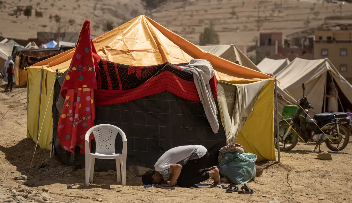 Seorang penyintas gempa Maroko berdoa di depan tenda yang digunakan sebagai tempat berlindung sementara, di Amizmiz di pegunungan High Atlas pada 14 September 2023. (FADEL SENNA / AFP)