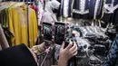 Pedagang menunjukkan sejumlah pakaian melalui aplikasi online (daring) di Pasar Tanah Abang, Jakarta, Rabu (1/7/2020). Pedagang Pasar Tanah Abang mulai menjual barang secara daring untuk menambah penjualan dan mengantisipasi turunnya jumlah pembeli di masa PSBB Transisi. (Liputan6.com/Faizal Fanani)