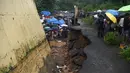 Petugas penyelamat dan warga berkumpul di lokasi runtuhnya tembok di Mumbai, India (2/7/2019). Sedikitnya 15 orang tewas dan 69 orang lainya luka ketika sebuah tembok runtuh saat hujan lebat monsun. (AFP Photo/Punit Paranjpe)