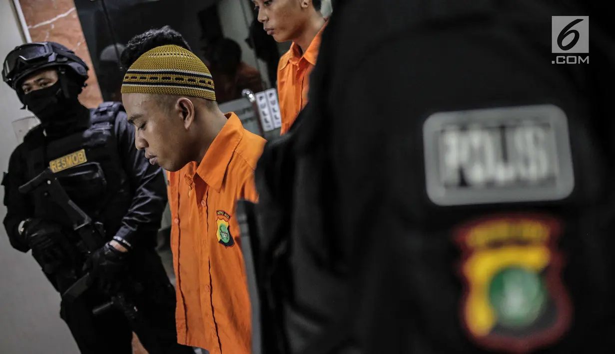 Aparat kepolisian berjaga dekat tersangka saat rilis sejumlah kasus kejahatan di Resmob Polda Metro Jaya, Rabu (6/3). Pada rilis gabungan itu petugas berhasil mengungkap sebanyak lima kasus. (Liputan6.com/Faizal Fanani)