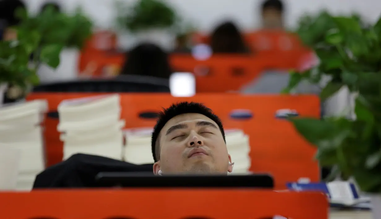 Seorang pegawai terlihat sangat nyenyak ketika tidur siang pada jam istirahat di kantornya, di Beijing, China, (21/4). Kegiatan tidur siang di kantor ini sudah menjadi budaya atau kebiasaan. (REUTERS/Jason Lee)