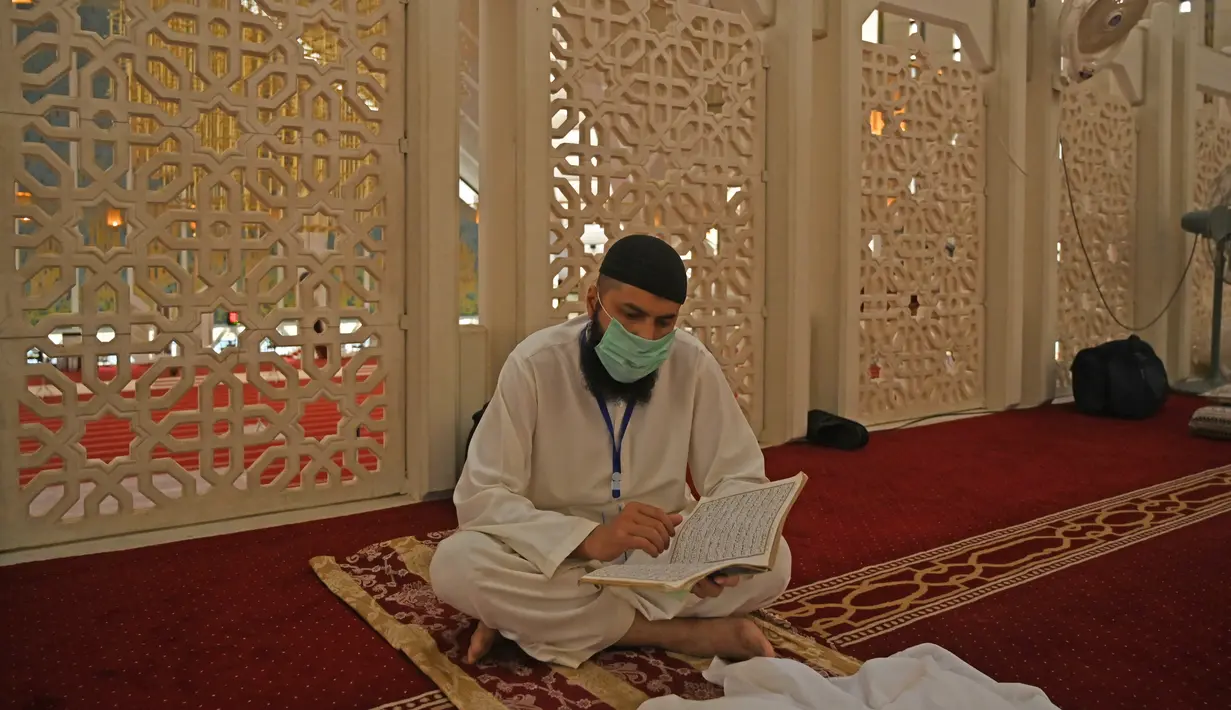 Pria Muslim dengan mengenakan masker saat membaca Alquran saat beritikaf di Masjid Agung Faisal di Islamabad, Pakistan, Kamis (14/5/2020). Itikaf adalah berdiam diri di masjid dengan niat beribadah untuk mendekatkan diri kepada Allah swt pada sepuluh hari terakhir bulan Ramadan. (Aamir QURESHI/AFP)