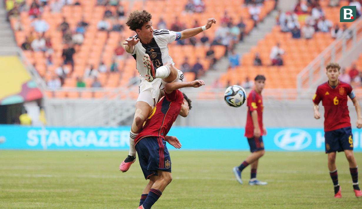 Pemain Timnas Jerman U-17, Noah Darvich, berebut bola dengan pemain Spanyol U-17, Quim Junyent pada laga perempat final Piala Dunia U-17 2023 di Jakarta International Stadium, Jumat (24/11/2023). Jerman menang dengan skor tipis 1-0. (Bola.com/M Iqbal Ichsan)