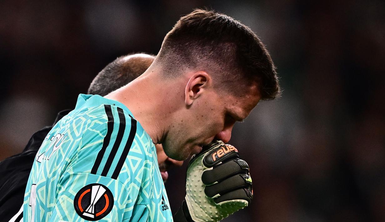 Kiper Juventus, Wojciech Szczesny berjalan meninggalkan lapangan dibantu oleh tim medis setelah mengalami sakit dada ketika pertandingan leg pertama perempat final Liga Europa 2022/2023 melawan Sporting CP di Allianz Stadium, Turin, Jumat (14/04/2023). Szczesny diketahui terkena paltisipasi jantung atau kondisi di mana seseorang merasakan kerja jantung yang kuat, cepat, atau tidak teratur. (AFP/Marco Bertorello)