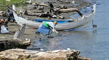 Para duta wisata Agam-Inong (laki-perempuan) membersihkan sampah plastik dan sampah lainnya yang terdampar di pantai selama kampanye di sebuah pantai di Banda Aceh pada 29 Oktober 2023. (CHAIDEER MAHYUDDIN/AFP)