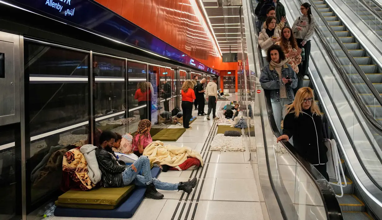 Orang-orang berlindung di stasiun metro bawah tanah saat sirene serangan udara memperingatkan datangnya rudal Iran di Tel Aviv, Israel, Sabtu, 7 Maret 2026. Sirene serangan udara di Tel Aviv, Israel, kembali meraung menyusul gelombang baru serangan rudal dari Iran. (AP Photo/Ohad Zwigenberg)