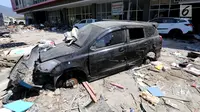 Sebuah mobil Datsun menjadi incaran jarahan korban gempa dan tsunami di Palu Grand Mal, Palu, Jumat (5/10). Warga korban gempa bumi mengambil ban dan interior mobil. (Liputan6.com/Fery Pradolo)