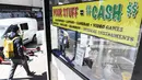 Pejalan kaki melewati papan nama yang menawarkan uang tunai untuk barang berharga di luar toko gadai di Los Angeles, Jumat (11/3/2022). Laju inflasi AS pada Februari 2022 melonjak ke level tertinggi dalam 40 tahun didorong naiknya harga bensin, makanan dan perumahan. (Patrick T. FALLON/AFP)