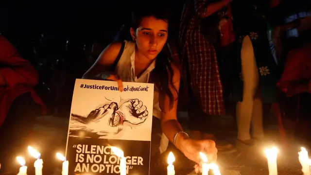 Seorang wanita India menyalakan lilin saat menggelar aksi protes kasus perkosaan di Ahmadabad, India (16/4). Selain itu dipicu juga oleh kasus penculikan serta pemerkosaan seorang gadis remaja di negara bagian utara Uttar Pradesh