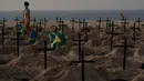 Seorang perempuan berjalan di antara ratusan kuburan di pantai Copacabana, Rio de Janeiro, Kamis (11/6/2020). Aksi simbolis yang dilakukan oleh kelompok LSM Rio de Paz itu sebagai bentuk protes atas respons pemerintah Brasil dalam menangani pandemi Covid-19. (AP Photo/Leo Correa)