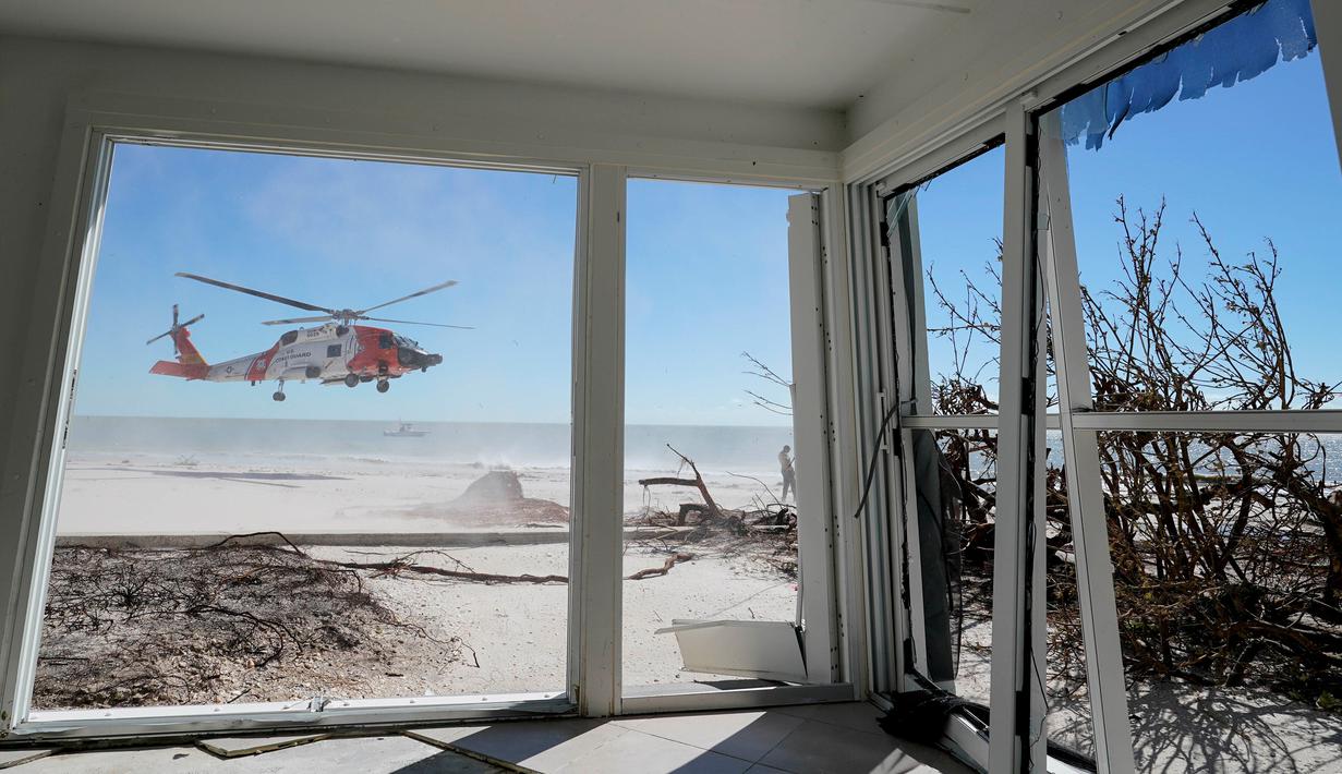 Helikopter Penjaga Pantai AS terlihat lepas landas dari dalam rumah yang rusak akibat Badai Ian di Pulau Sanibel, Florida, 30 September 2022. Badai Ian tengah jadi sorotan di AS, sebab terjangannya begitu dahsyat hingga meninggalkan jejak kerusakan dan korban jiwa. (AP Photo/Steve Helber)