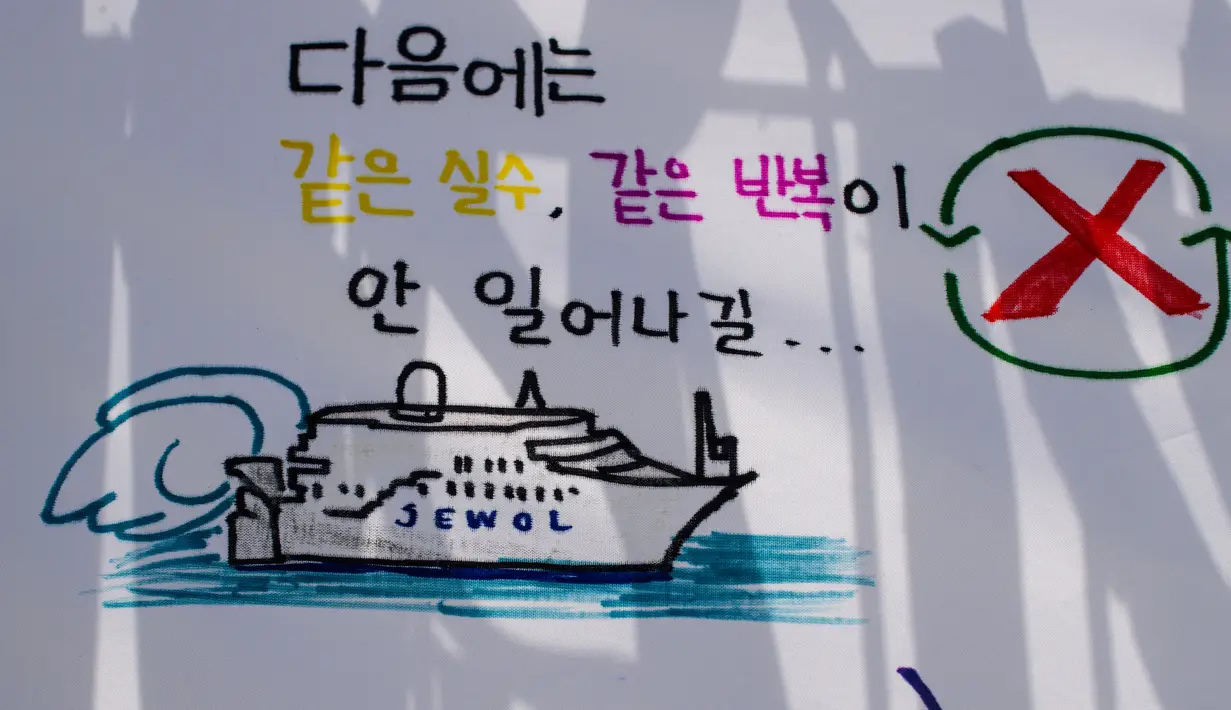 Sebuah gambar yang menggambarkan kapal feri Sewol dengan tulisan yang diterjemahkan sebagai "Saya harap kesalahan yang sama tidak akan terjadi lagi di lain waktu", di sebuah pelabuhan di Mokpo, Provinsi Jeolla Selatan, pada tanggal 16 April 2024. (ANTHONY WALLACE/AFP)