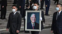James Zhao, cucu menantu mantan Presiden Taiwan Lee Teng-hui membawa potret Lee saat prosesi pemakaman di Pemakaman Militer Wuzhi Mountain di New Taipei City, Rabu (7/10/2020). Lee, yang dianggap sebagai "bapak demokrasi Taiwan", meninggal Juli lalu di usia 97 tahun. (Military News Agency via AP)