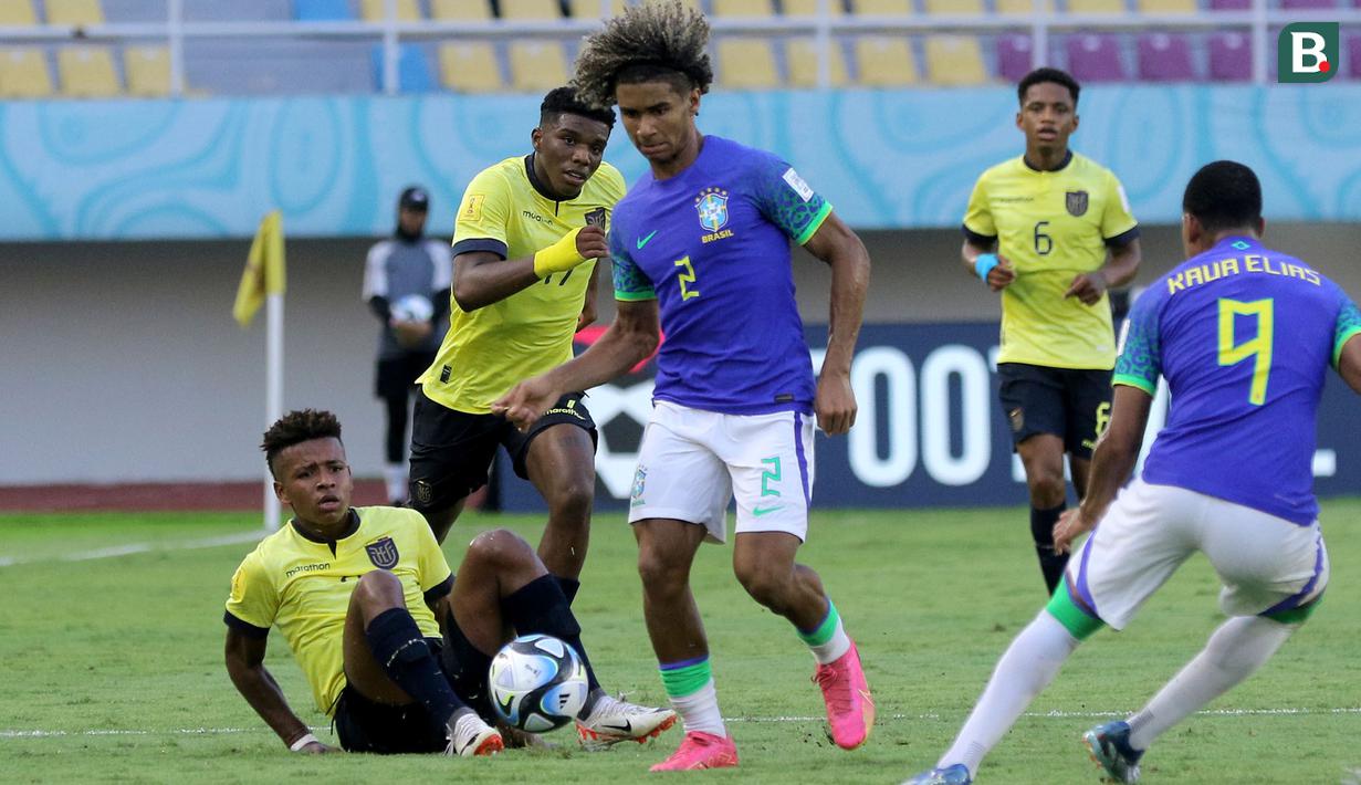 <p>Pemain Timnas Brasil U-17, Pedro Lima (tengah) berusaha melewati hadangan pemain Ekuador U-17 dalam pertandingan babak 16 Besar Piala Dunia U-17 di Stadion Manahan, Solo, Senin (20/11/2023). (Bola.com/Arief Bagus)</p>