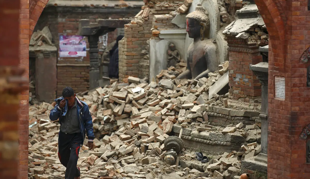 Seorang pria menangis saat berjalan diantara reruntuhan patung Buddha pasca gempa bumi di Bhaktapur, Nepal, (26/4/2015). (REUTERS/Navesh Chitrakar)