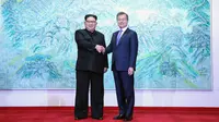Pemimpin Korea Utara Kim Jong Un berjabat tangan dengan Presiden Korea Selatan Moon Jae-in saat menggelar pertemuan di Peace House, Panmunjom, Korea Selatan, Jumat (27/4). Keduanya membahas terkait nuklir Korea Utara. (Korea Summit Press Pool via AFP)