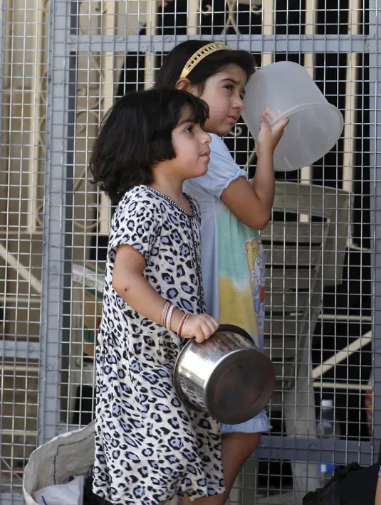 Dua anak perempuan menunggu makanan buka puasa gratis yang didistribusikan bagi yang membutuhkan selama bulan puasa di masjid Abdul Qadir al-Gailani, Baghdad, Rabu (24/6/2015). (REUTERS/Khalid al-Mousily)