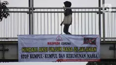Pejalan kaki melintasi Jembatan Penyeberangan Orang (JPO) di Jalan Raya Lenteng Agung, Jakarta, Selasa (17/3/2020). Sebuah spanduk berisi ajakan menghindari kerumunan dan kumpul-kumpul untuk mencegah penyebaran virus Corona COVID-19 terpasang di JPO teresebut. (Liputan6.com/Helmi Fithriansyah)