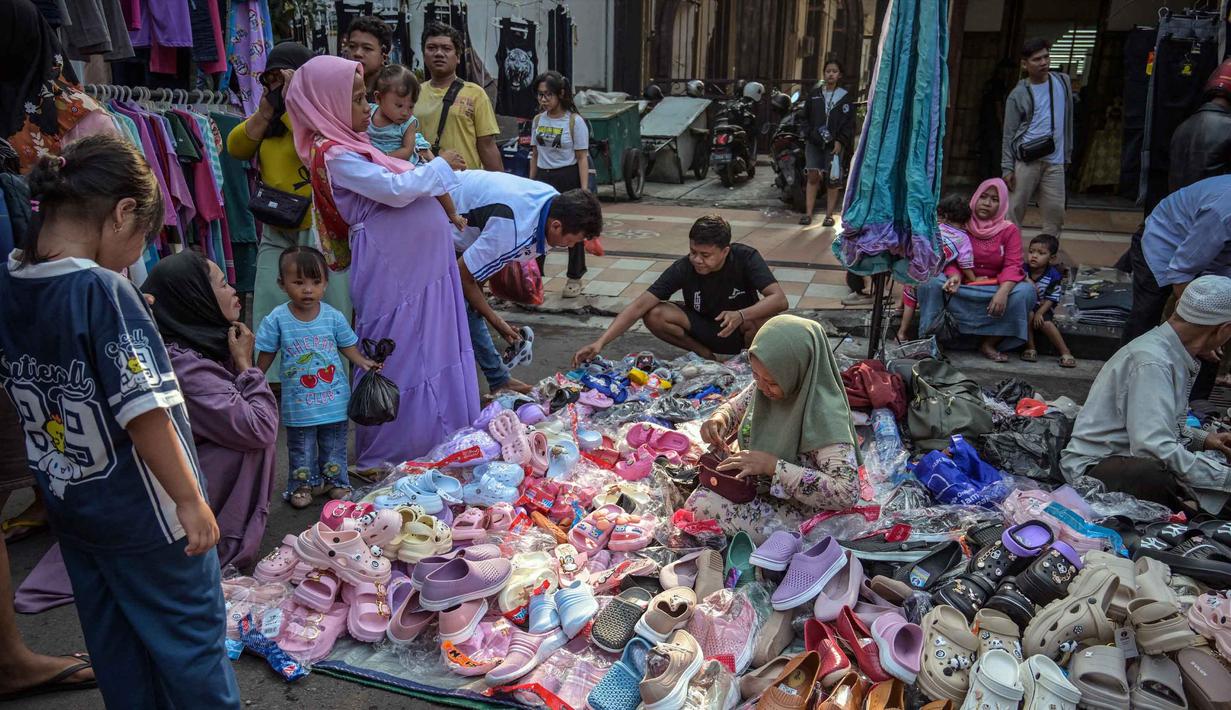 Untuk data yang dikumpulkan addalah karakteristik usaha, permodalan/investasi, kendala usaha, kinerja/daya saing, serta adopsi ekonomi digital. Tampak dalam foto, orang-orang berbelanja sepatu dan sandal di sebuah kios pakaian di salah satu ruas jalan, Surabaya, Jawa Timur, pada Minggu 19 April 2026. (JUNI KRISWANTO/AFP)