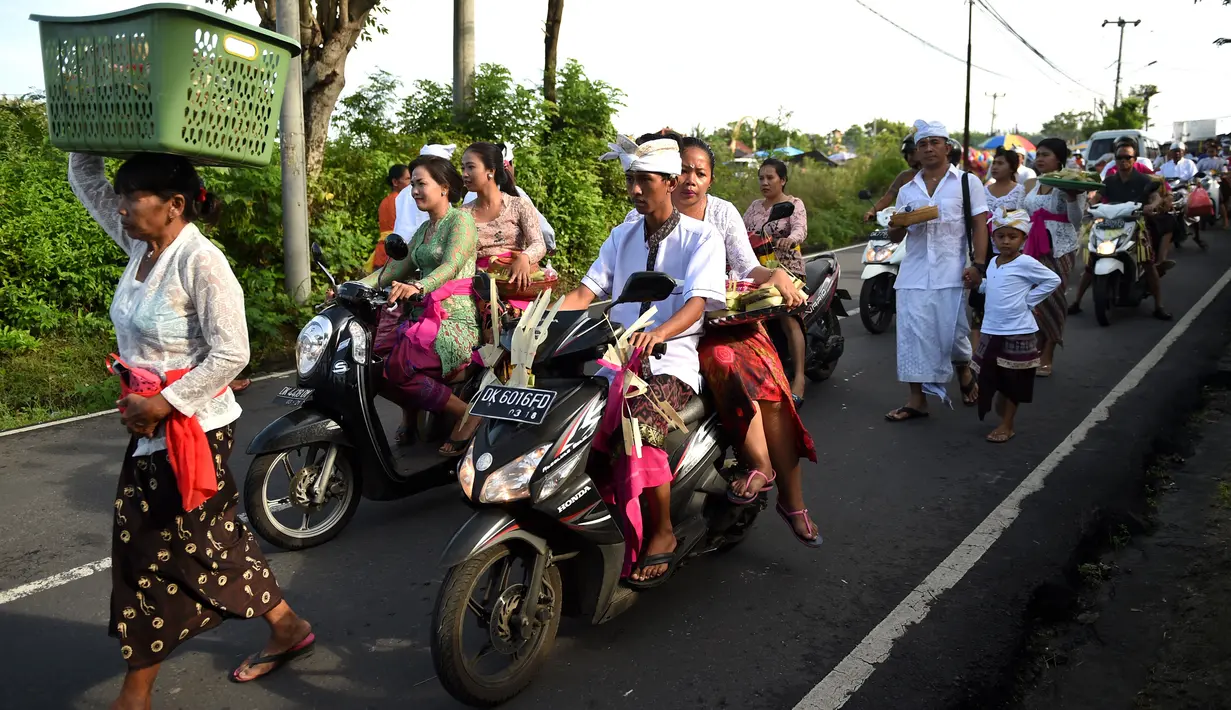 Umat Hindu menuju pura untuk sembahyang Hari Raya Galungan di Jimbaran, Bali, Rabu (5/4). Galungan dimaknai sebagai hari kemenangan Dharma (Kebaikan) melawan Adharma (Keburukan) yang dirayakan dengan persembahyangan di tiap Pura. (SONNY TUMBELAKA/AFP)