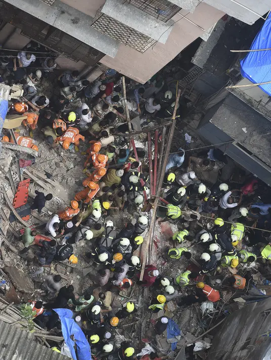 Petugas pemadam kebakaran India mencari korban setelah sebuah bangunan ambruk di Mumbai (16/7/2019). Dua orang tewas dan sedikitnya 40 terperangkap di bawah puing-puing setelah bangunan ambruk ketika hujan lebat. (AFP Photo/Punit Paranjpe)