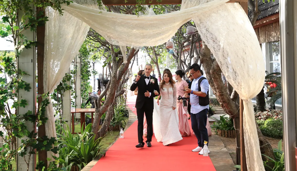 Senyuman semringah begitu terpancar dari wajah keduanya yang menggelar pesta pernikahan di tepi pantai. Suasana begitu hangat lantaran hadirnya para sahabat dan kerabat yang turut berbahagia di acara mereka. (Nurwahyunan/Bintang.com)