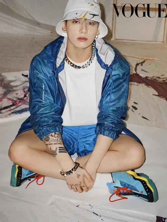 Anggota termuda BTS, Jungkook mengenakan atasan 2054 printed windbreaker jacket Louis Vuitton warna biru dipadukan tshirt putih dan short pants warna senada. Aksesoris sepeti bucket, kalung, dan anting pun dipilih olehnya. Sneakers biru melengkapi penampilannya. Dok. Vogue Korea