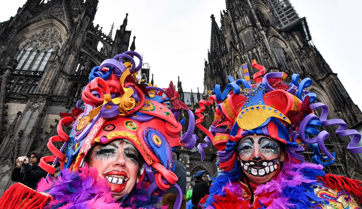 Perempuan dengan kostum warna-warni berpose di depan katedral Cologne saat puluhan ribu orang menyambut dimulainya musim karnaval di jalan-jalan Kota Cologne, Jerman, Senin (11/11/2019). Musim karnaval ini dikenal juga sebagai musim kelima dalam satu tahun. (AP Photo/Martin Meissner)