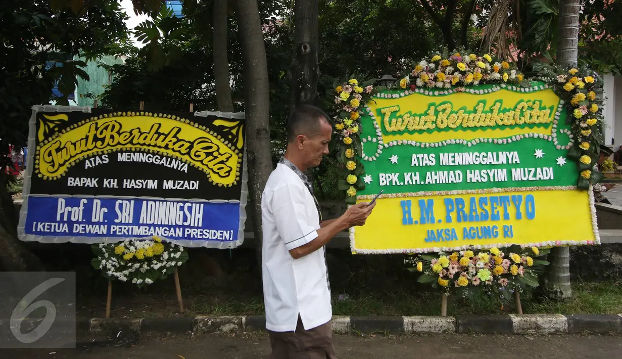 Warga melintas di depan Karangan bunga yang menghiasi rumah duka tokoh PBNU KH Hasyim Muzadi di Ponpes Al-Hikam, Depok, Jawa Barat, Kamis (16/3). Karangan bunga mulai berdatangan pascameninggalnya KH Hasyim Muzadi. (Liputan6.com/Immanuel Antonius)