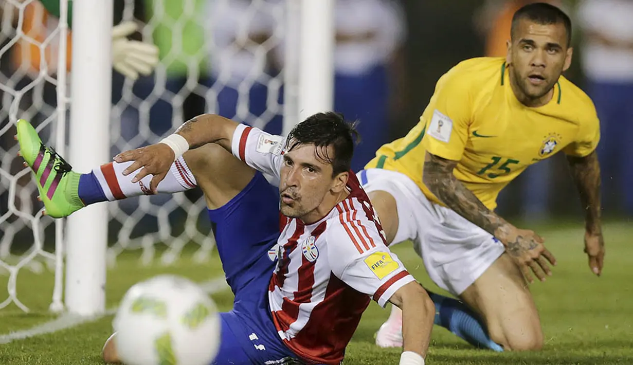 Gelandang Paraguay, Edgar Benitez, terjatuh berebut bola dengan bek Brasil, Dani Alves, pada kualifikasi Piala Dunia 2018 di Stadiom Chaco, Paraguay, Rabu (30/3/2016). Kedua tim bermain imbang 2-2. (Reuters/Jorge Adorno)