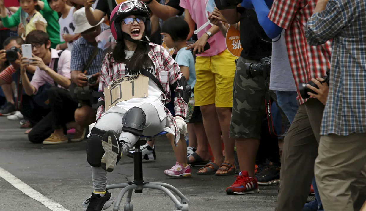 Seorang peserta wanita tertawa ketika memeriahkan balapan berlari menggunakan kursi kantor dalam kompetisi ISU-1 Grand Prix di Tainan, Taiwan Selatan, Minggu (24/4/2016).  (REUTERS/Tyrone Siu)