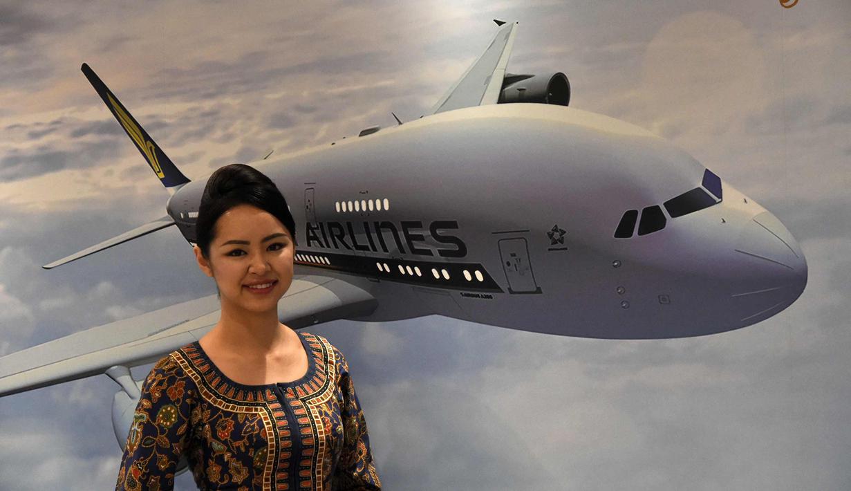 Pramugari berpose di depan poster SIA Airbus A380 saat peluncuran kabin terbaru di Singapura, (2/11). Kabin first class, business class, dan economy class ini tersedia di lima pesawat Airbus A-380 Singapore Airlines. (AFP Photo/Roslan Rahman)