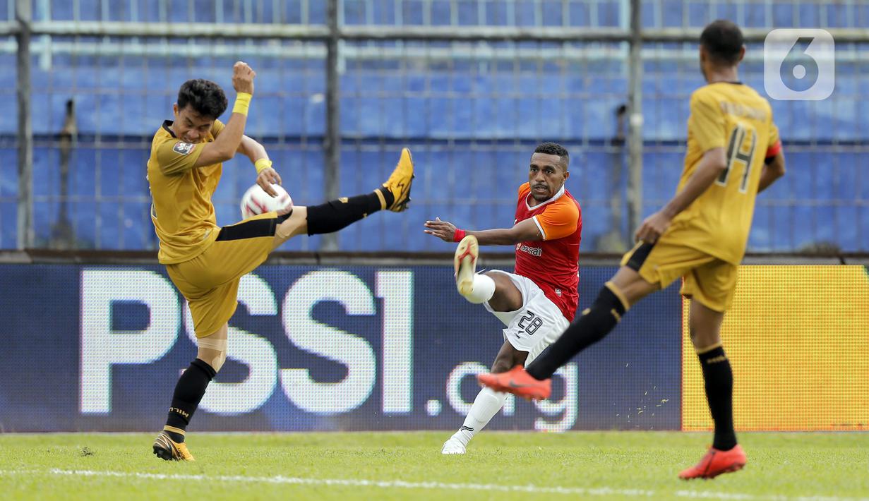 Pemain Bhayangkara Solo FC menghalau bola tembakan dari pemain Borneo FC Samarinda Terens Owang Priska Puhiri (tengah) dalam pertandingan Babak Penyisihan Piala Menpora 2021 di Stadion Kanjuruhan, Malang, Senin (22/3/2021). (Bola.com/Arief Bagus)