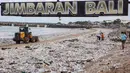 Tumpukan sampah ini menjadi keluhan wisatawan sekaligus memberikan tekanan ekonomi bagi pelaku usaha restoran di sepanjang garis pantai. Tampak dalam foto, para pekerja dan warga membersihkan ceceran dan tumpukan sampah plastik yang terdampar di Pantai Jimbaran, Bali, pada Selasa 10 Maret 2026. (Lana Priatna/AFP)