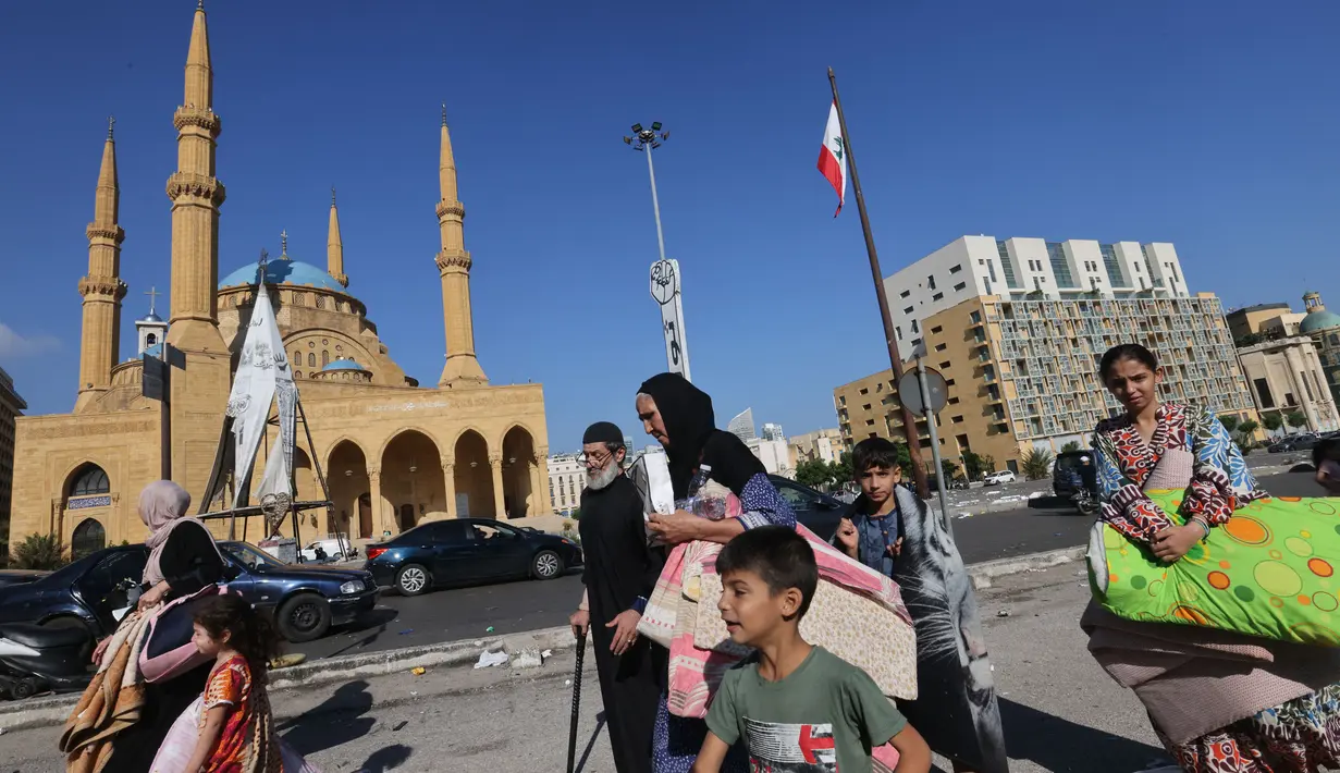 Orang-orang yang melarikan diri dari pengeboman Israel di pinggiran selatan Beirut, berkumpul dengan barang-barang mereka di Martyrs Square di pusat ibu kota Lebanon di mana mereka bermalam pada 28 September 2024. (JOSEPH EID/AFP)