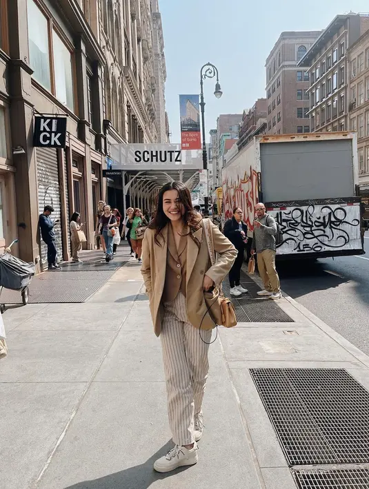 Ia padukan sleevlees blazer dengan blazer cokelat dan striped pants yang kece [@aaliyah.massaid]