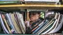 Seorang anak mencari buku untuk dibaca di perpustakaan Bale Buku Meleduk (Membaca Literasi Dukuh) 75 di Jalan Dukuh V, Kelurahan Dukuh, Kecamatan Kramat Jati, Jakarta Timur, Rabu (24/8/2022). Selain itu, gerakan Hanjaba juga sebagai upaya mewujudkan generasi yang cinta membaca dan cinta perpustakaan. (merdeka.com/Iqbal S. Nugroho)
