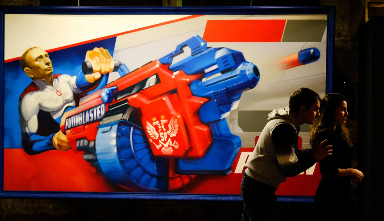 Dua orang pengunjung melihat pameran Superputin di Museum Umam, Moskow (6/12). Pameran ini menampilkan lukisan, patung, mosaik, kolase, dan bahkan aneka mainan yang menggambarkan sang pemimpin Rusia tersebut.(AFP Photo/Yuri Kadobnov)