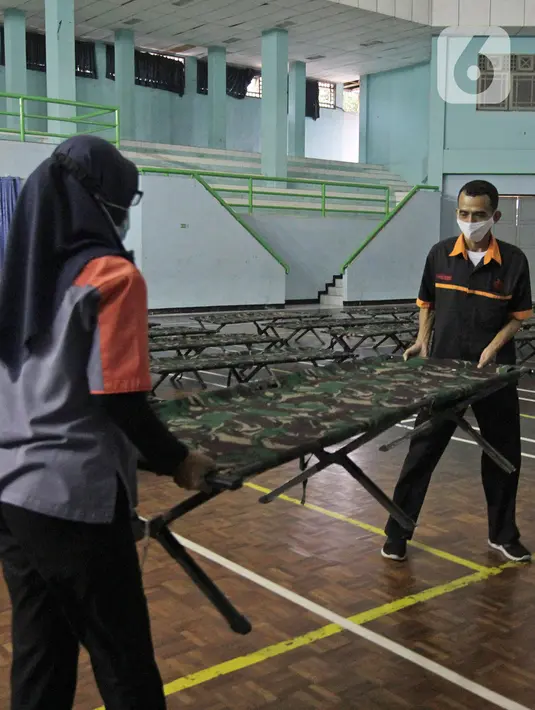 Petugas menyiapkan tempat singgah sementara bagi warga yang baru kembali ke Jakarta di GOR Cipayung, Jakarta, Selasa (18/5/2021). GOR ini jadi tempat singgah bagi mereka yang tidak memiliki tempat layak untuk isolasi mandiri sambil menunggu hasil tes swab antigen/PCR. (Liputan6.com/Herman Zakharia)