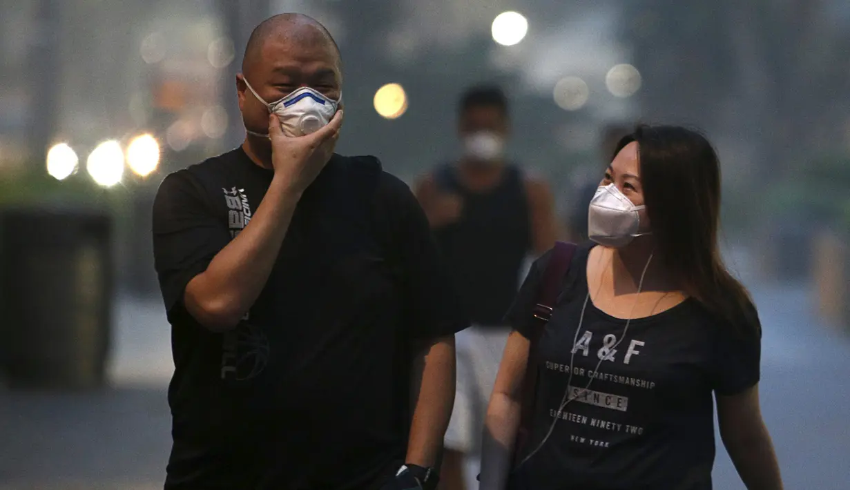 Sejumlah warga memakai masker saat berjalan di pusat perbelanjaan Orchard Road, Singapura (25/9/2015). Menurut Badan Lingkungan Nasional Singapura kabut Polutan Standar Indeks (PSI) mencapai tinggi 341 pada hari Jumat. (REUTERS/Edgar Su)