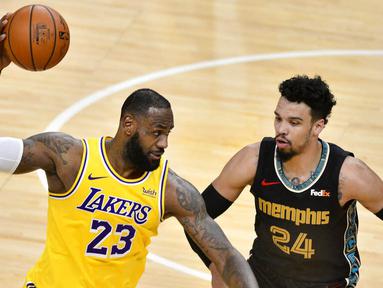 Pebasket Los Angeles Lakers, LeBron James, berusaha melewati pebasket Memphis Grizzlies, Dillon Brooks, pada laga NBA, Rabu (6/1/2021). LA Lakers menang tipis 94-92 atas Grizzlies. (AP Photo/Brandon Dill)